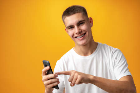 Young casual man teenager using a smartphone against yellow backgroundの写真素材