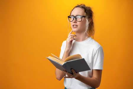 Cute pretty girl with books on yellow background