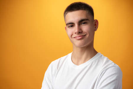 Portrait of a teen boy smiling against yellow background