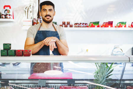 Portrait of confident young salesman standing in butchers shopの写真素材