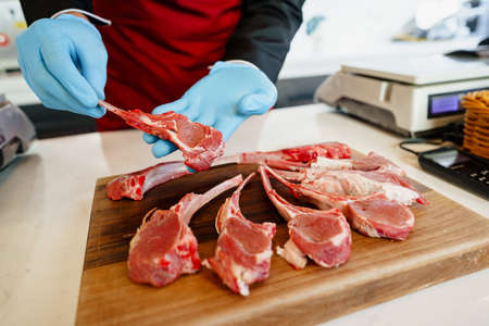 Close up of a butcher setting raw lamb ribs in a butcher shopの写真素材