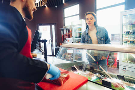 Female customer against raw meat stall section in food storeの写真素材