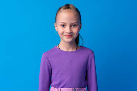 Portrait of a little smiling girl preteen on blue backgroundの写真素材