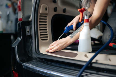 Woman cleaning car salon with polishing spray in car detailing serviceの写真素材