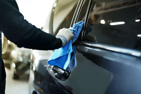 Close up of male car service worker applying nano coating on a car