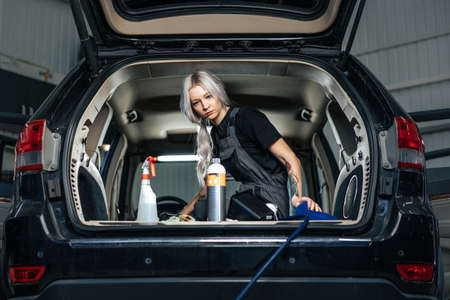 Woman cleaning car salon with polishing spray in car detailing serviceの写真素材