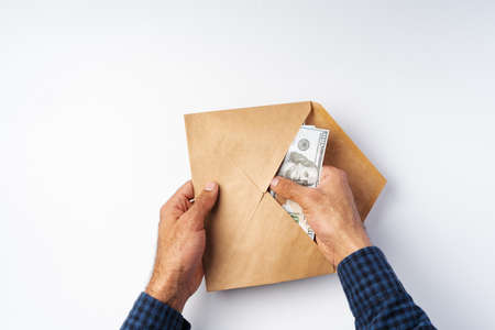 Male hands opening an envelope and take out US Dollars above white backgroundの写真素材