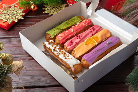 Box of colorful eclairs on Christmas background