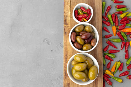 Composition with chili peppers, olives and olive oil on gray background