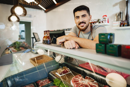 Portrait of confident young salesman standing in butchers shop