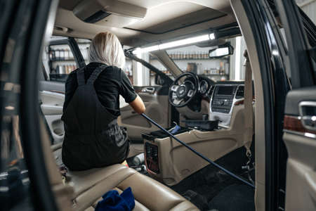 Worker woman vacuum cleaning dust interior inside car in car wash.の写真素材