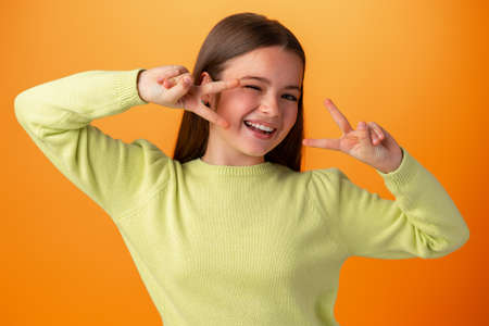 Teenager girl isolated on orange background showing victory sign