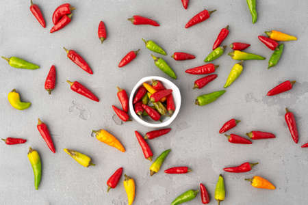 Mini chili peppers scattered on gray background top view