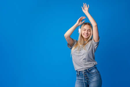 Happy young woman with headphones on a blue backgroundの写真素材
