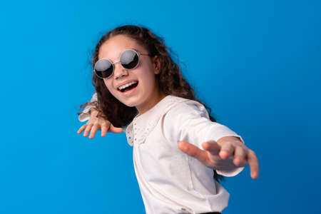 Little fashion girl in sunglasses against blue backgroundの写真素材