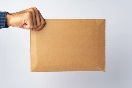 Male hand holding parcel post against white background, close upの写真素材