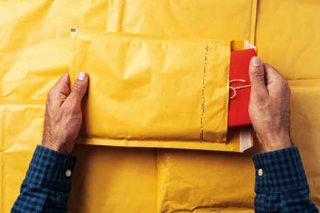 Male hands packing yellow bubble envelopes for shipping.の写真素材