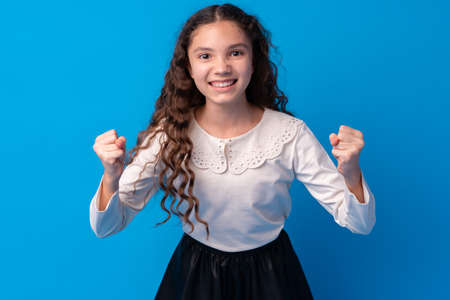 Little cute girl showing her strength on blue backgroundの写真素材