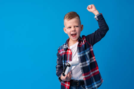 Little boy having fun playing with video console on blue backgroundの写真素材