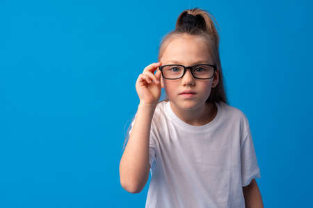 Teen girl adjusting her eyeglasses on blue backgroundの写真素材