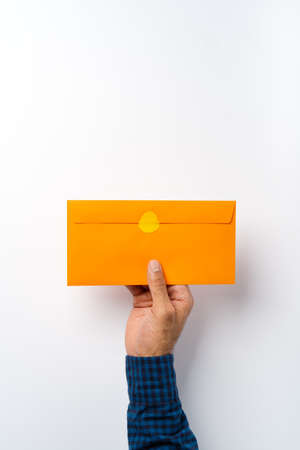 Male hand holding closed envelope above the white surfaceの写真素材