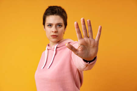 Teen girl showing stop sign palm against yellow backgroundの写真素材