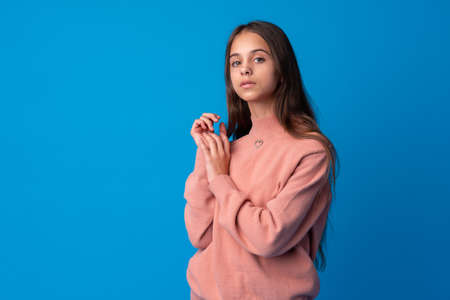 Portrait of a cute teen girl posing against blue backgroundの写真素材