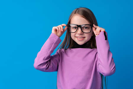 Portrait of a little smiling girl preteen on blue backgroundの写真素材