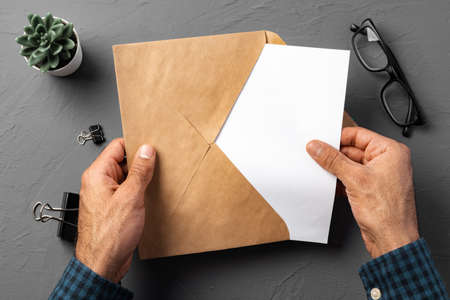 Business correspondence. Top view of man hands holding mockup envelope with letter. Copy space.の写真素材