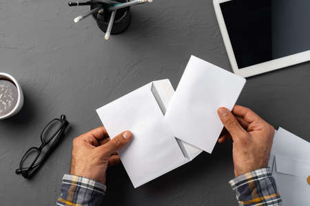 Business correspondence. Top view of man hands holding mockup envelope with letter. Copy space.の写真素材