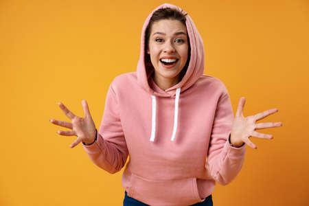 Surprised happy beautiful woman looking in excitement over yellow background