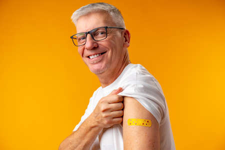 Senior man against yellow background received vaccination
