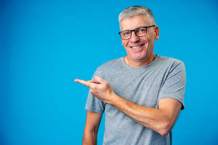 Happy mature man pointing finger to copy spaceの写真素材