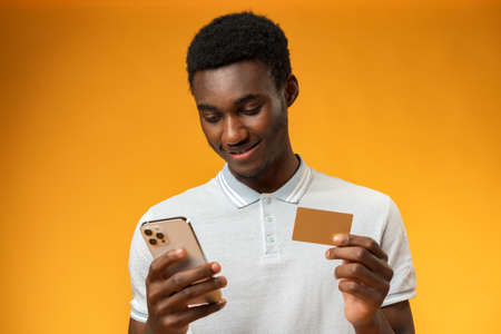Black man using credit card and smartphone for online shoppingの写真素材