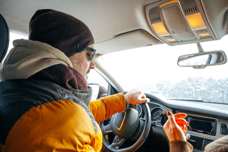 Man in warm winter clothes sitting in car and driving