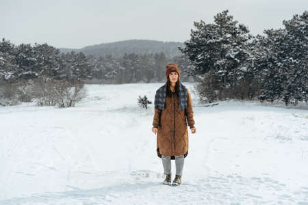 Woman in winter warm jacket walking in snowy winter forestの写真素材
