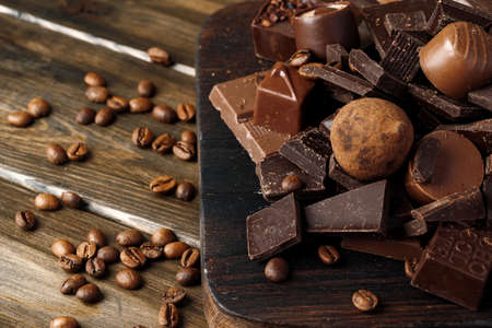 Chocolate pieces and candy on dark wooden table.の写真素材