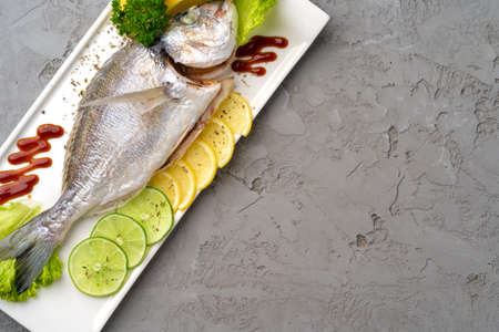 Fresh sea fish with lemon on plateの写真素材