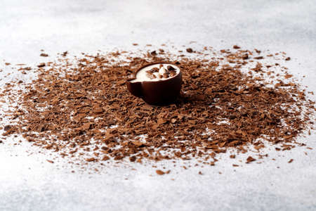 Grated chocolate and candy on gray background