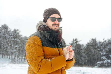 Young man in warm coat standing in snowy winter forestの写真素材