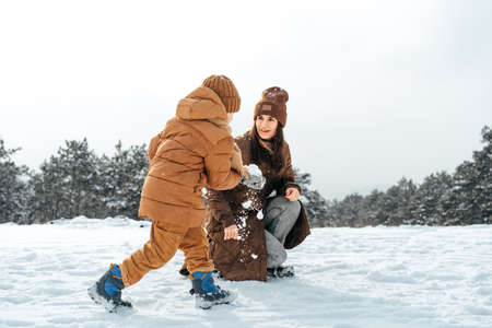 Woman with a little son on a winter hike in the snowy forest