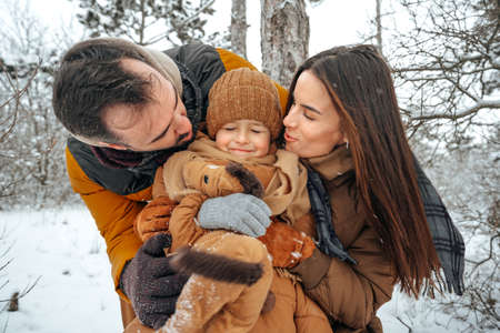 Portrait of happy family in winter clothes in forestの写真素材