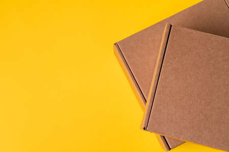 Beige cardboard boxes on yellow background, close upの写真素材