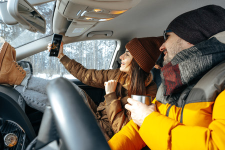 Family couple sitting in car in winter clothes iin snow forestの写真素材