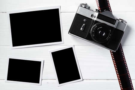 Old retro camera and photos on white wooden background