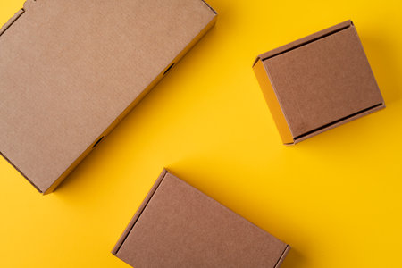 Beige cardboard boxes on yellow background, close upの写真素材