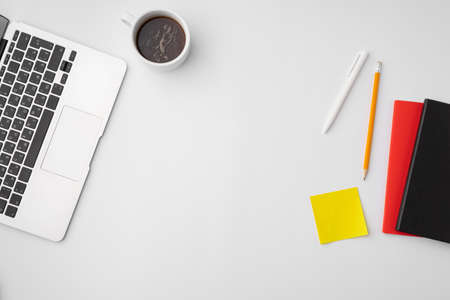 Office desk with laptop, blank notebook and coffee cupの写真素材