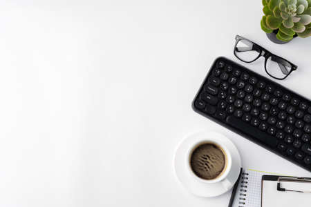 Office desk with laptop, blank notebook and coffee cupの写真素材