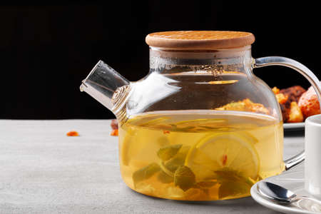Glass teapot with fruit tea and cookies on gray backgroundの写真素材