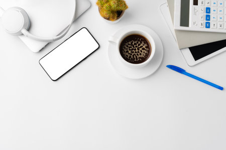Creative white table with blank cellphone and suppliesの写真素材